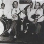 Caption from Ancestry.com: George Pariseau's sons played in his orchestra: Back row (left to right) Carl on drums, Ford on trumpet, and Harold on the piano. Front row: Dewey on the banjo and Cecil on the fiddle.
